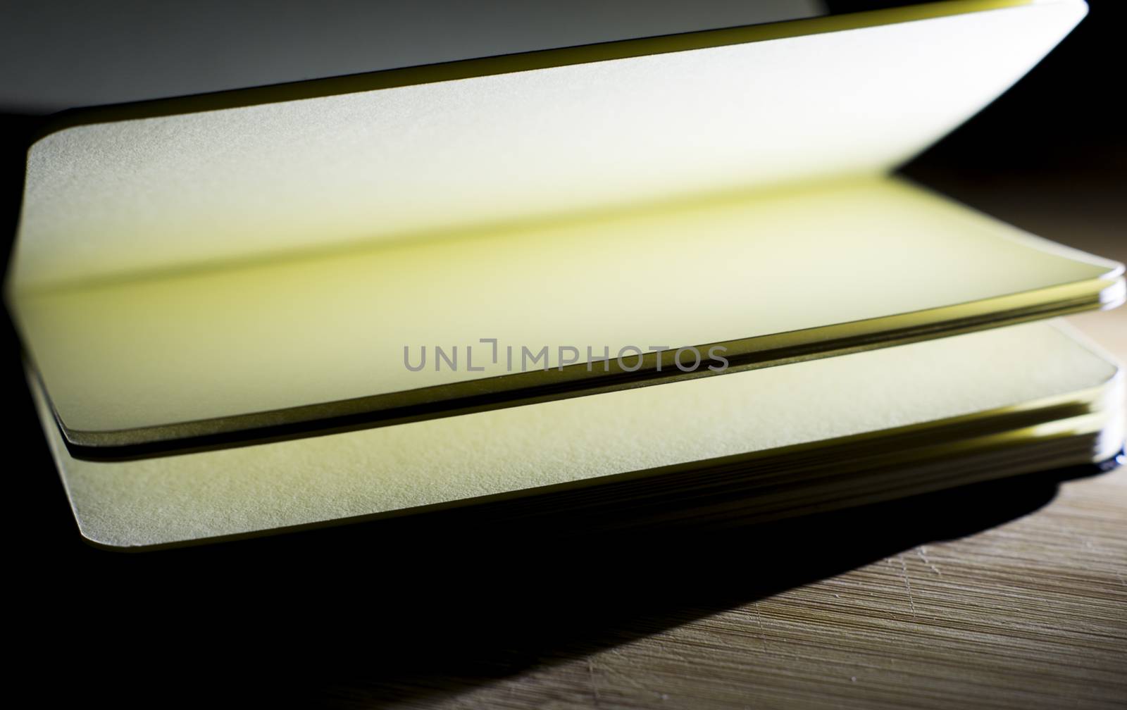 open book with incident light from the side on desk by serhii_lohvyniuk