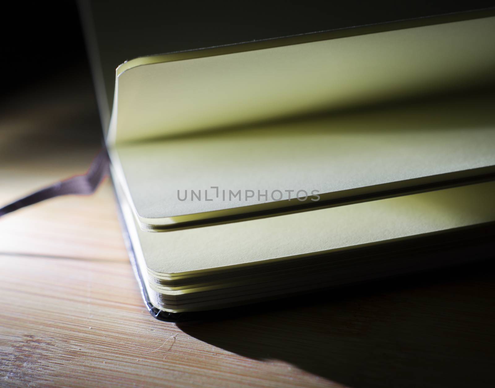 open book with incident light from the side on desk by serhii_lohvyniuk