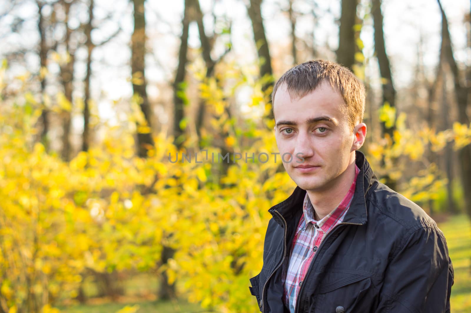 young attractive man a black jacket in autumn park by serhii_lohvyniuk