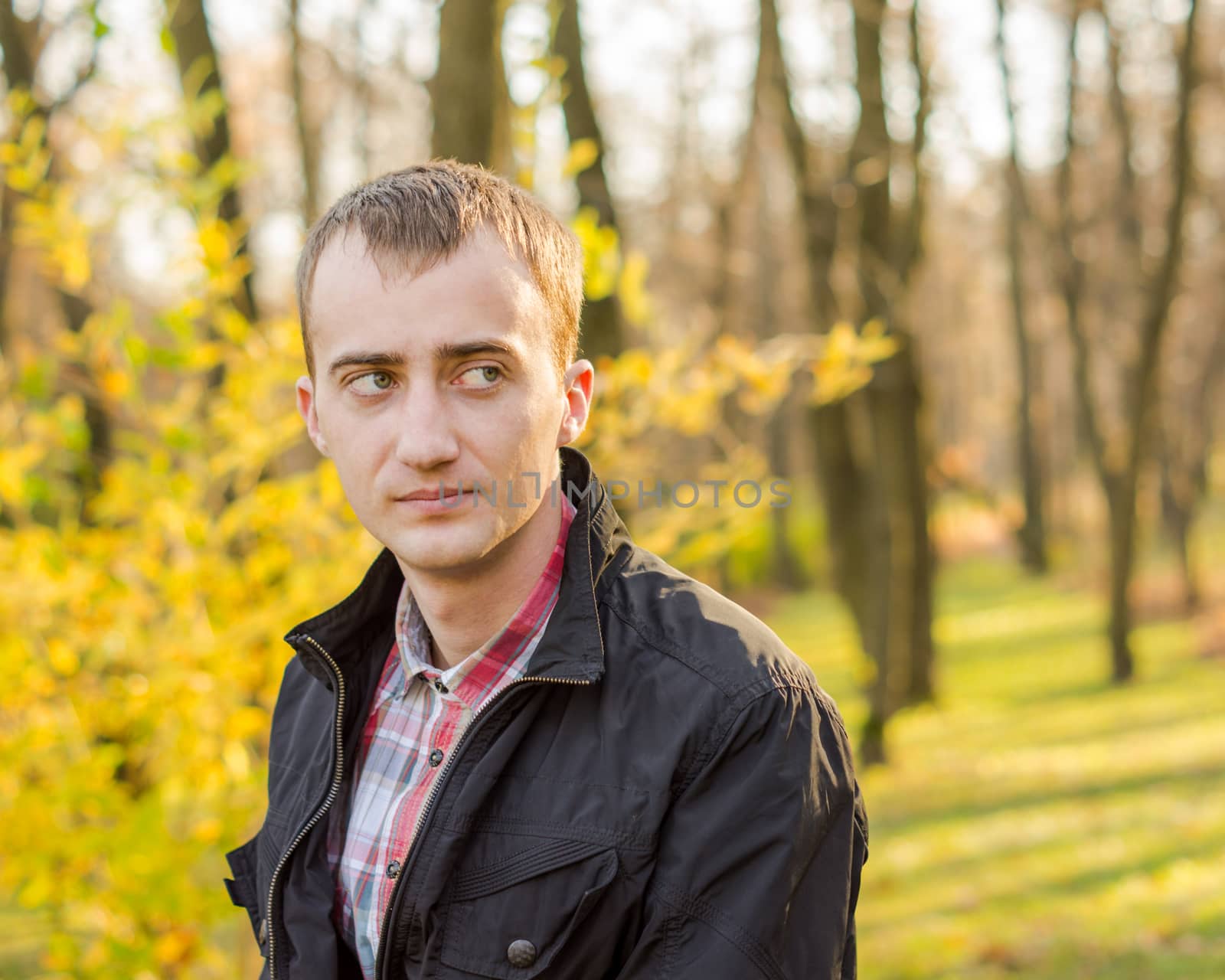young attractive man a black jacket in autumn park by serhii_lohvyniuk
