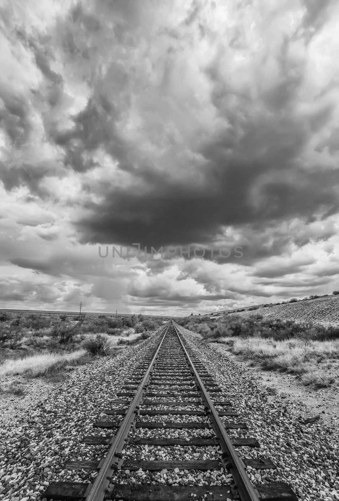 Black and white scene of empty railroad tracks in desert