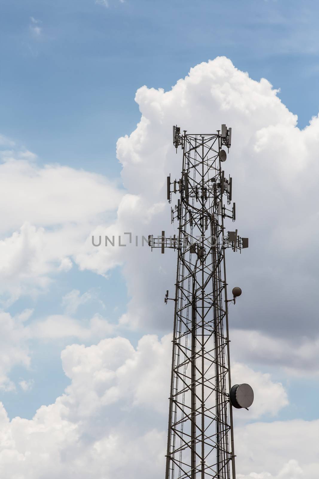 Single tall telecommunications tower with clouds in background