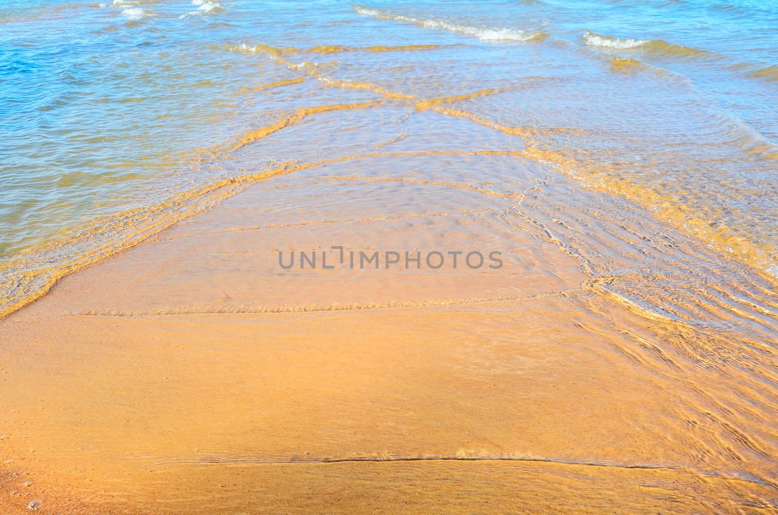 Transparent waves on the sandy beach