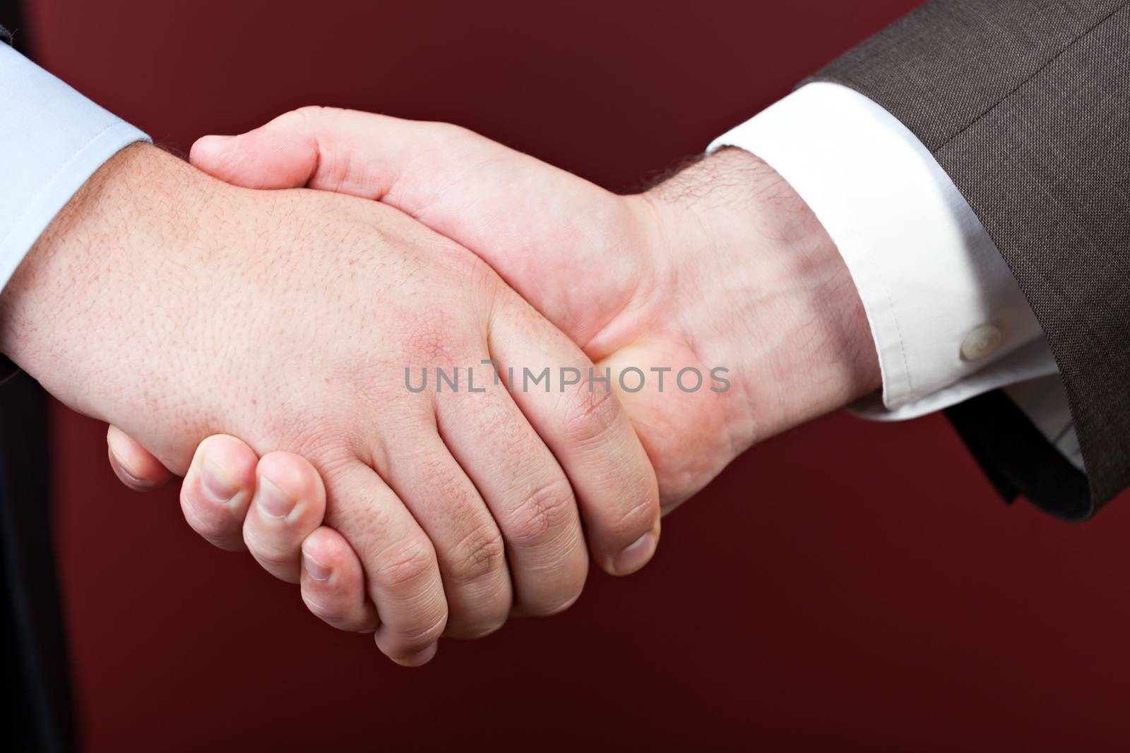 Business negotiations illustrated with a close up of a handshake between two men.