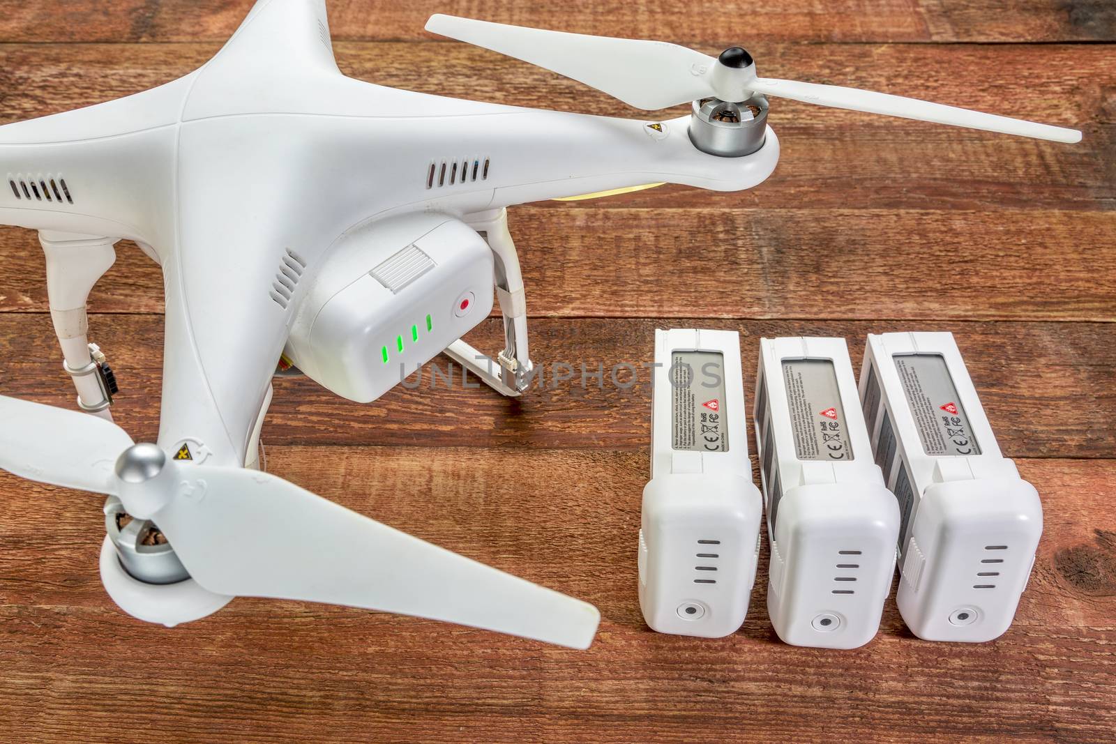 Fort Collins, CO, USA - March 17, 2015:  DJI Phantom 2 quadcopter drone with spare LiPo batteries, top view against rustic wooden table.