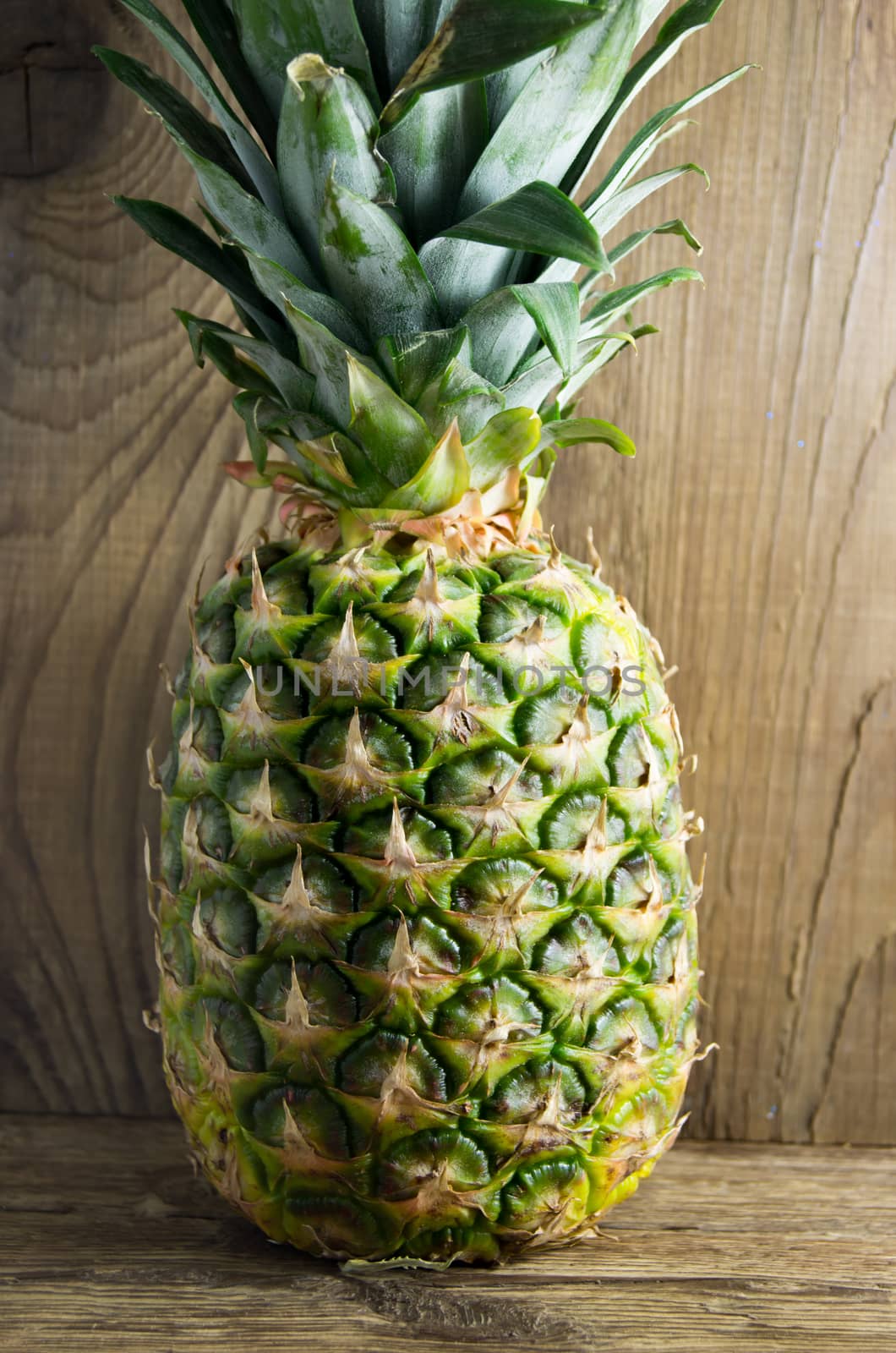 Ripe tasty pineapple lie on a wooden background.
