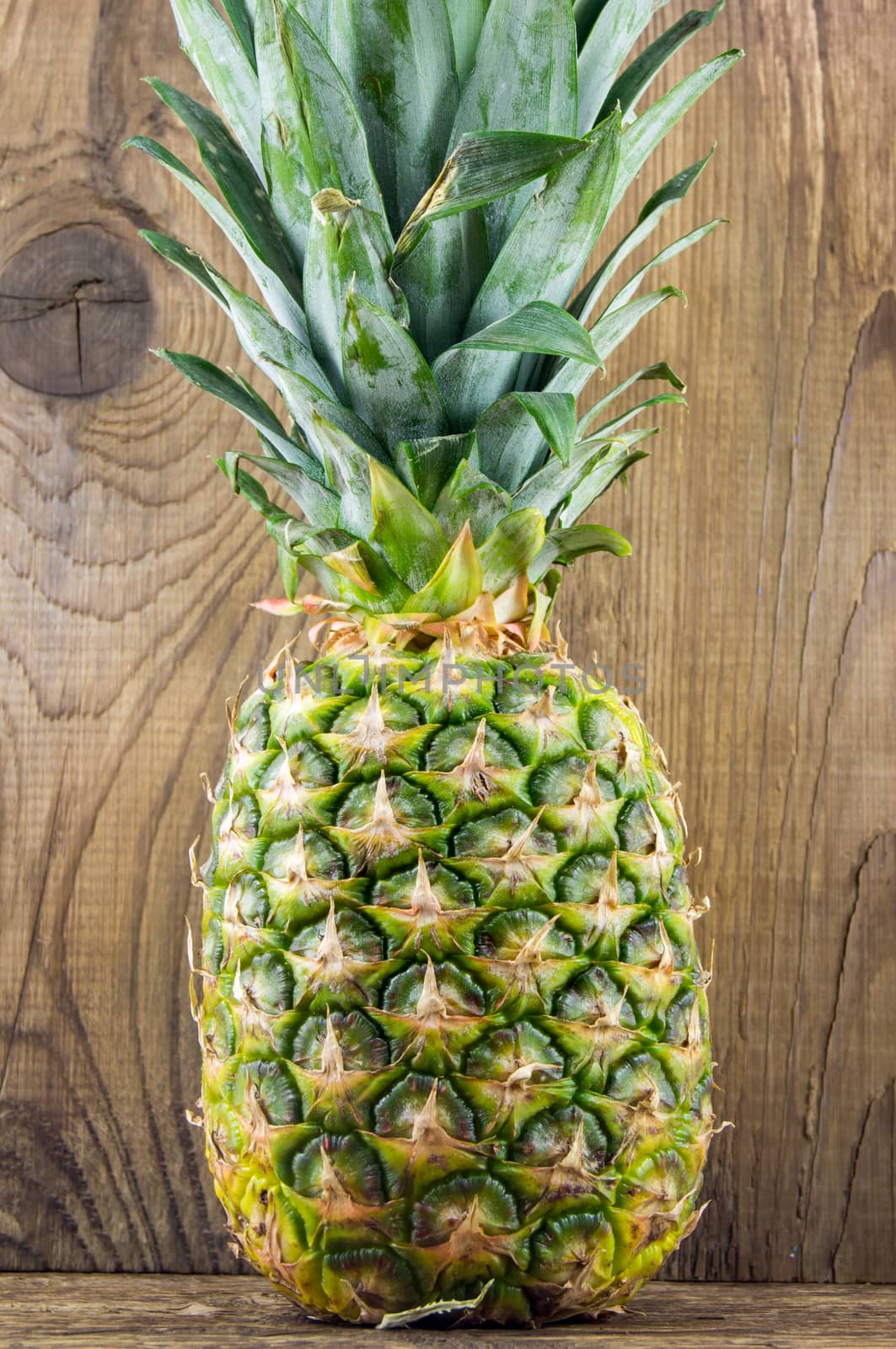 Ripe tasty pineapple lie on a wooden background.