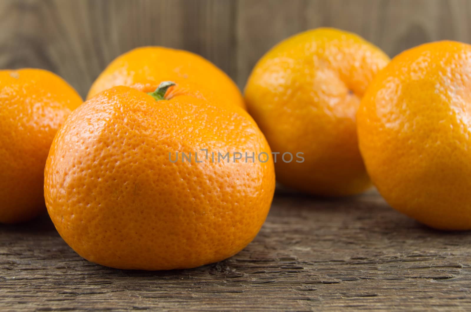 Ripe tangerines lie on a wooden background