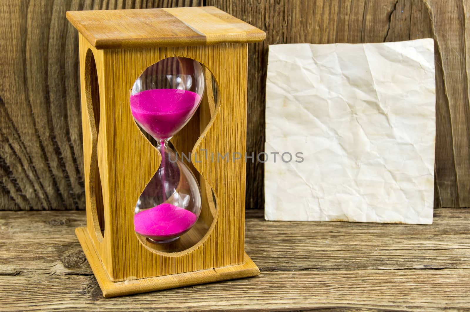 Hourglass with space for text on the wooden background.