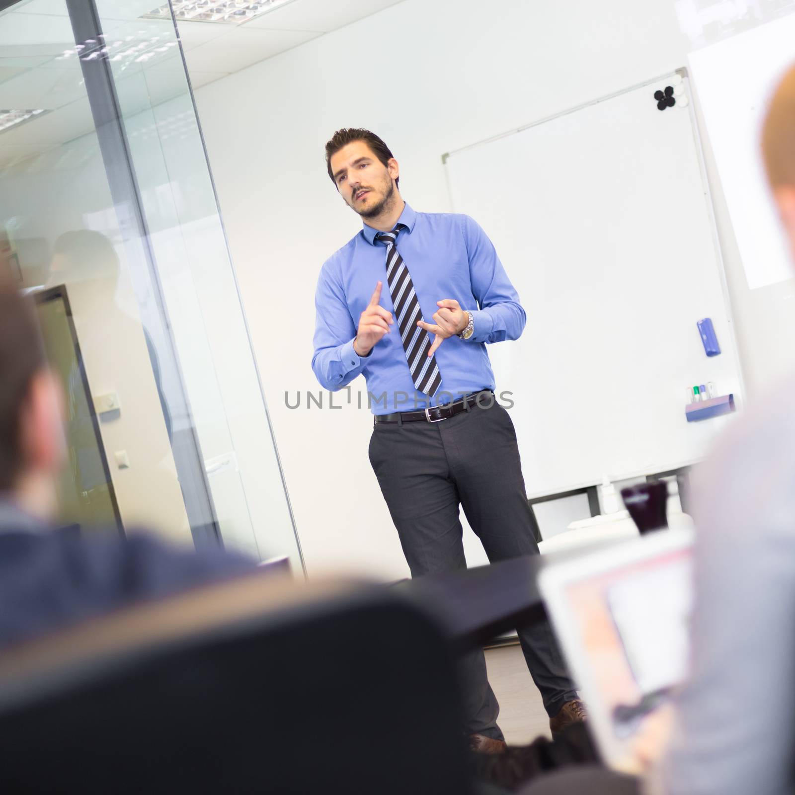 Business man making a presentation at office. Business executive delivering a presentation to his colleagues during meeting or in-house business training, explaining business plans to his employees.