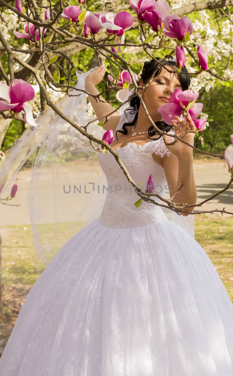 Young happy bride smells flowers magnolia outdoors. For your commercial and editorial use.