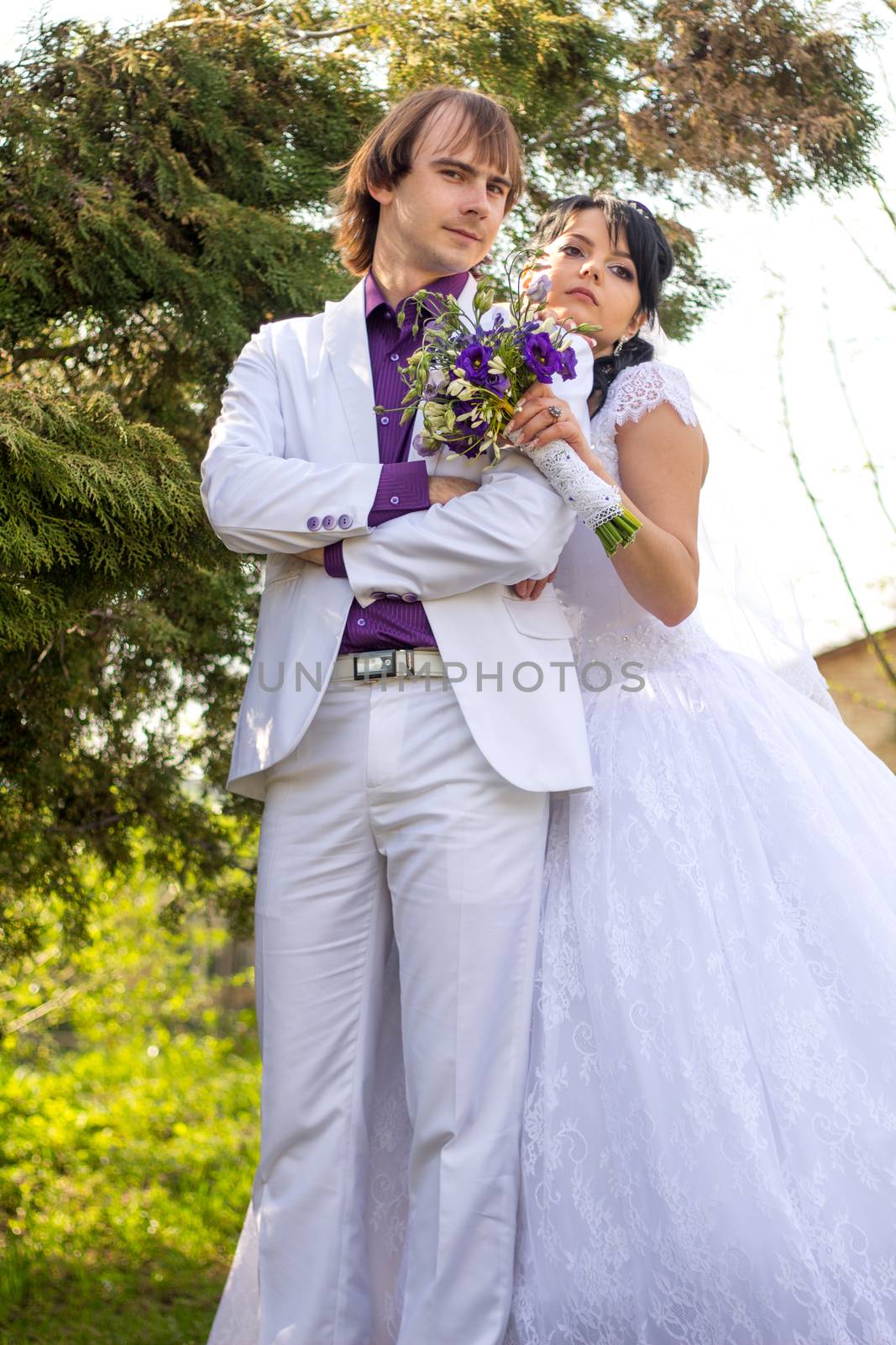 Elegant bride and groom posing together outdoors on a wedding da by serhii_lohvyniuk