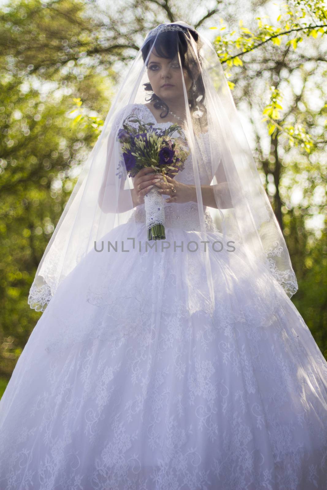 The bride is closed veil with a bouquet in hand. For your commercial and editorial use.