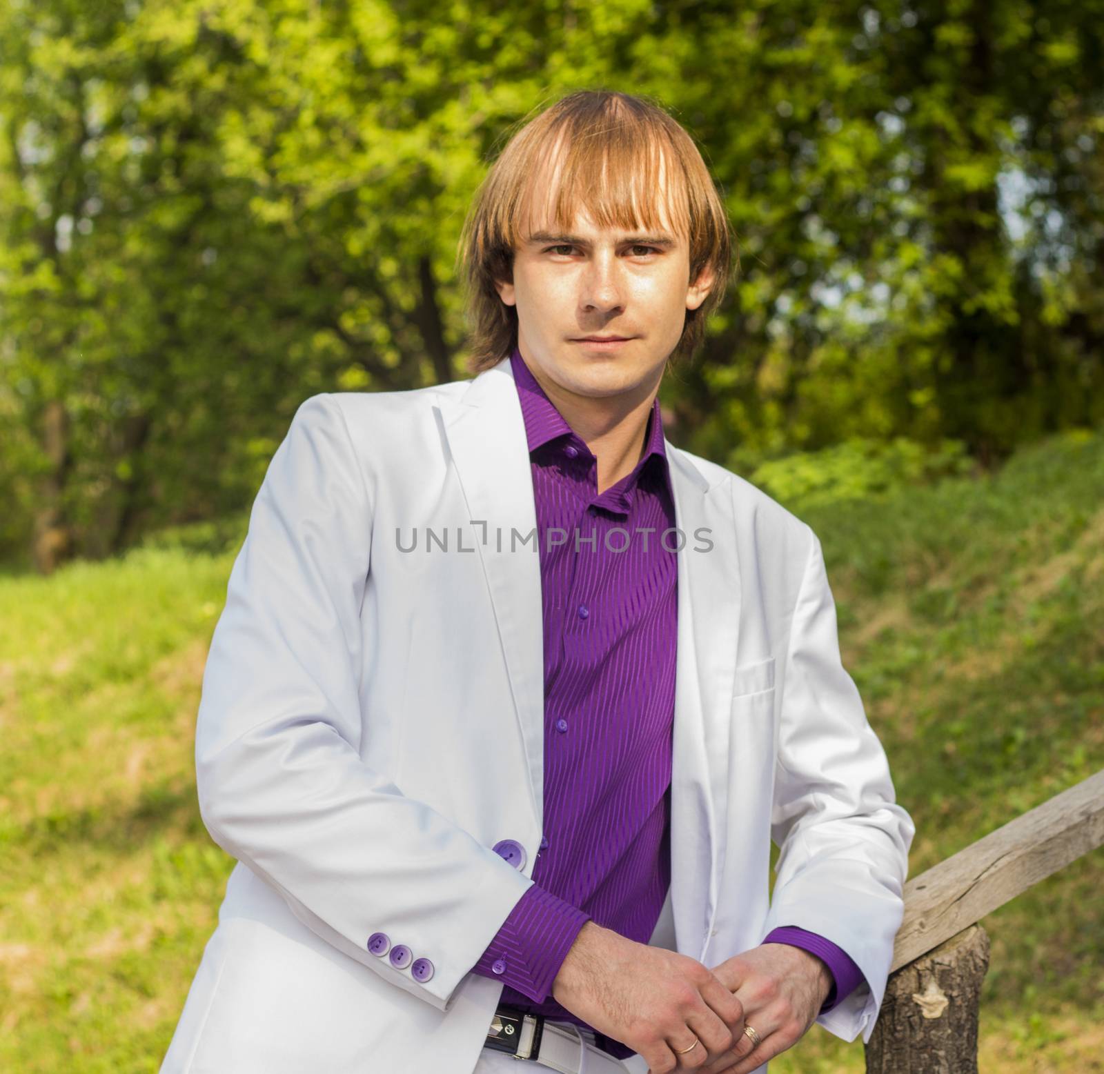 serious guy in the park a white suit and purple shirt by serhii_lohvyniuk