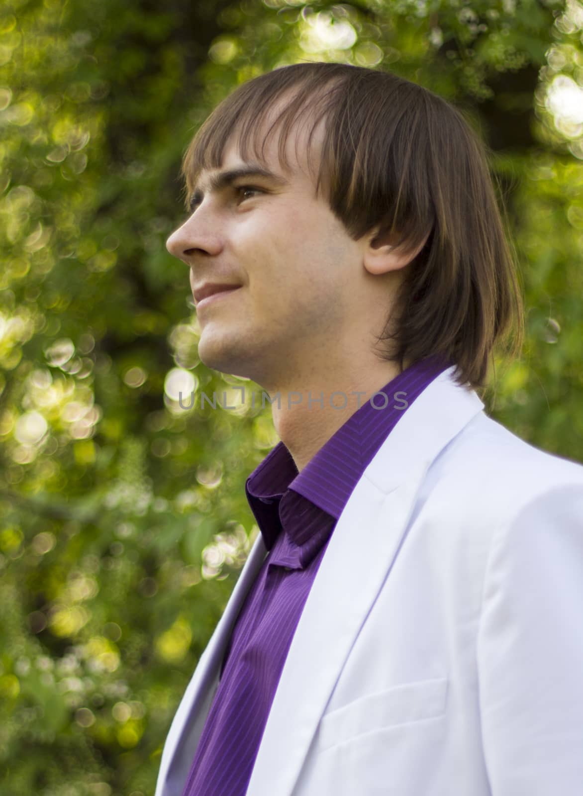 happy guy in the park a white suit and purple shirt.