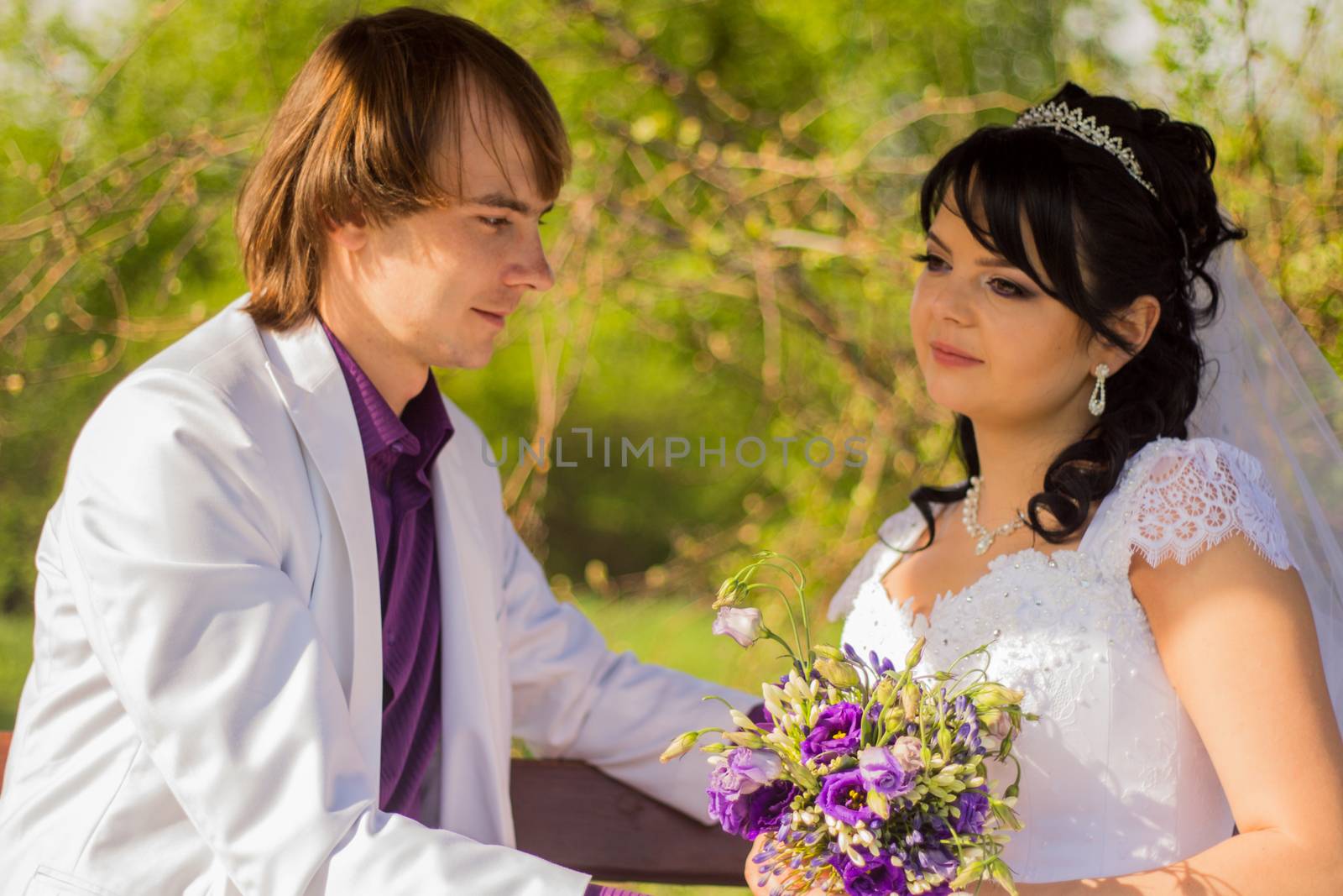 Romantic wedding couple sitting on a bench in the park.