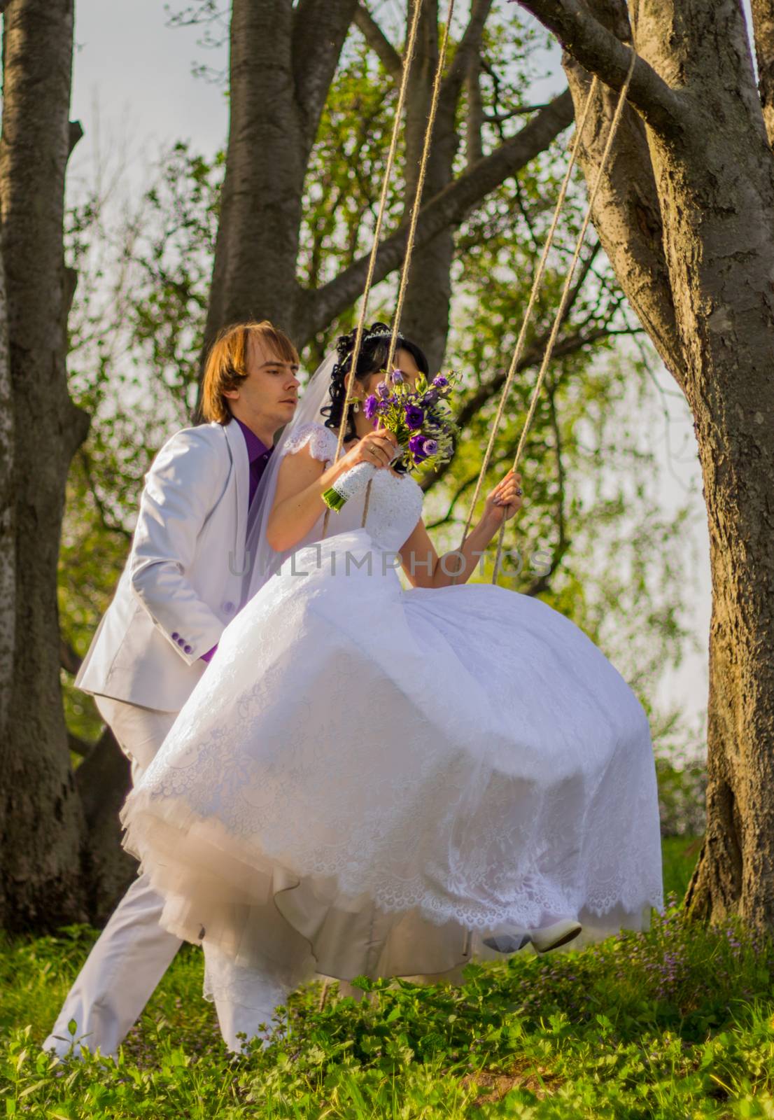 bride and groom swinging on a swing by serhii_lohvyniuk