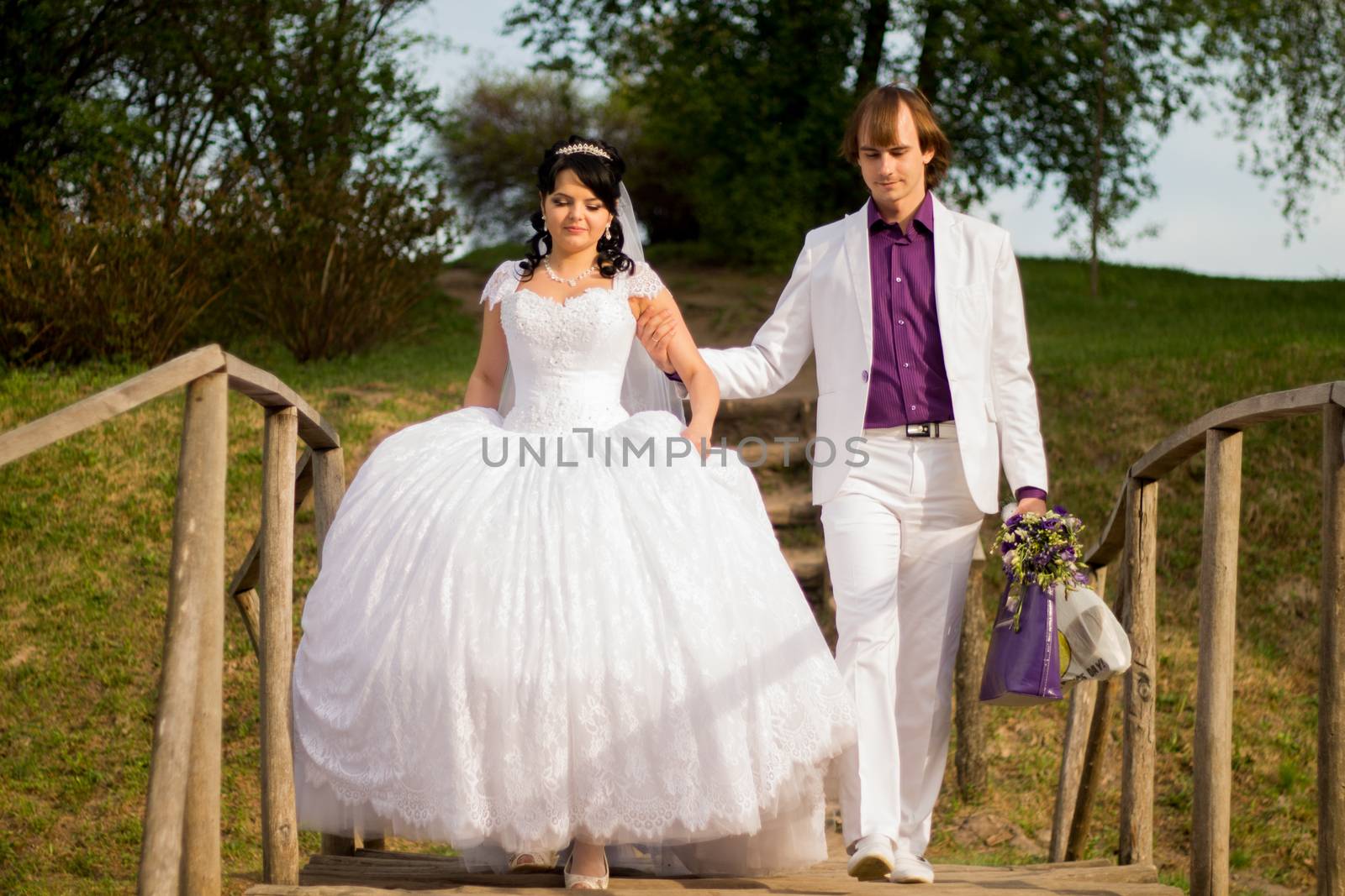 Happy just married couple standing on the small bridge.