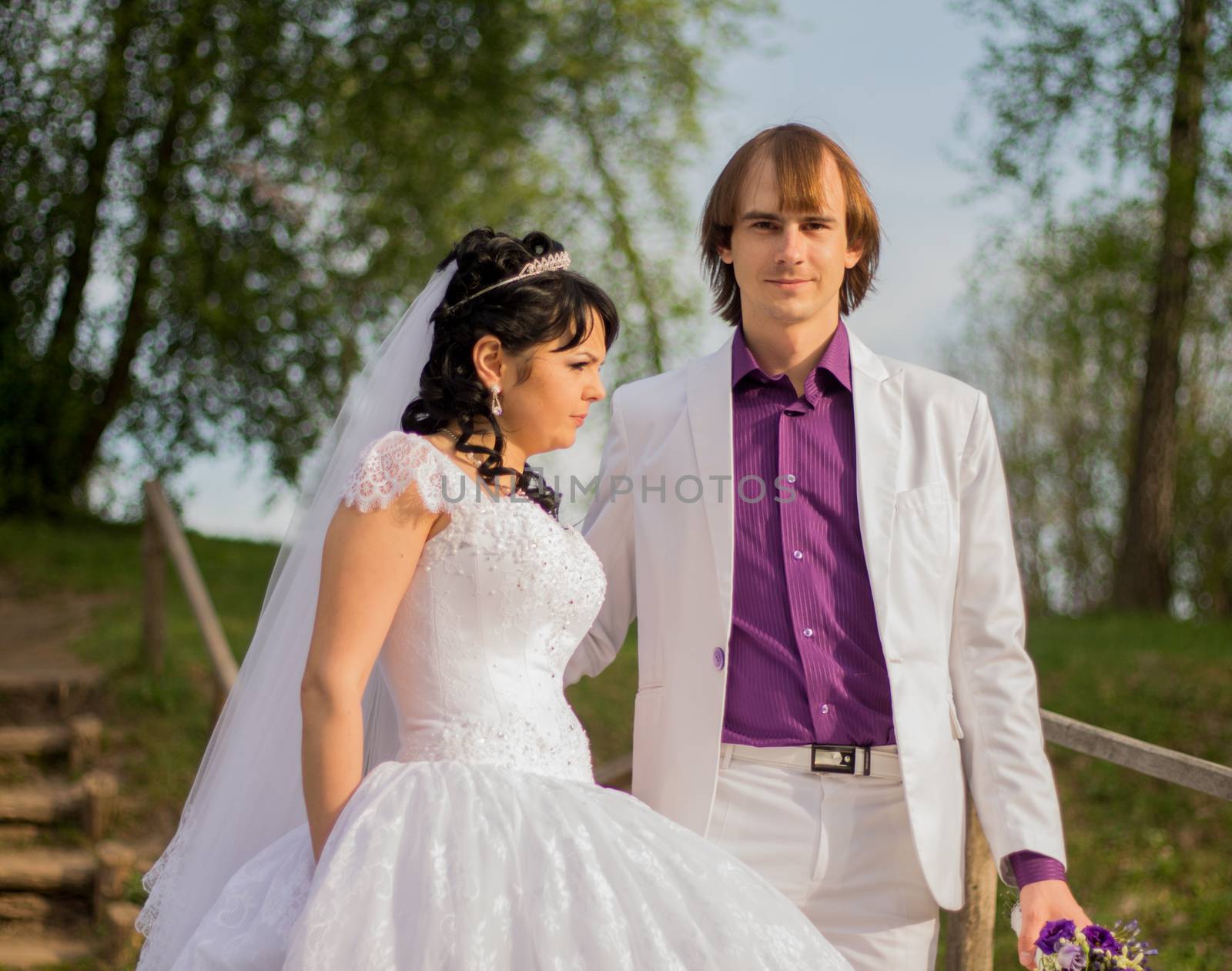 Happy just married couple standing on the small bridge.