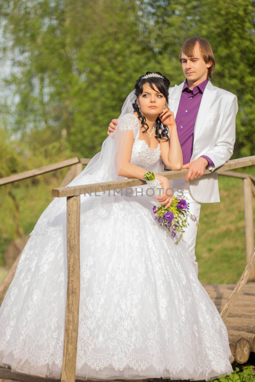 Happy just married couple standing on the small bridge.