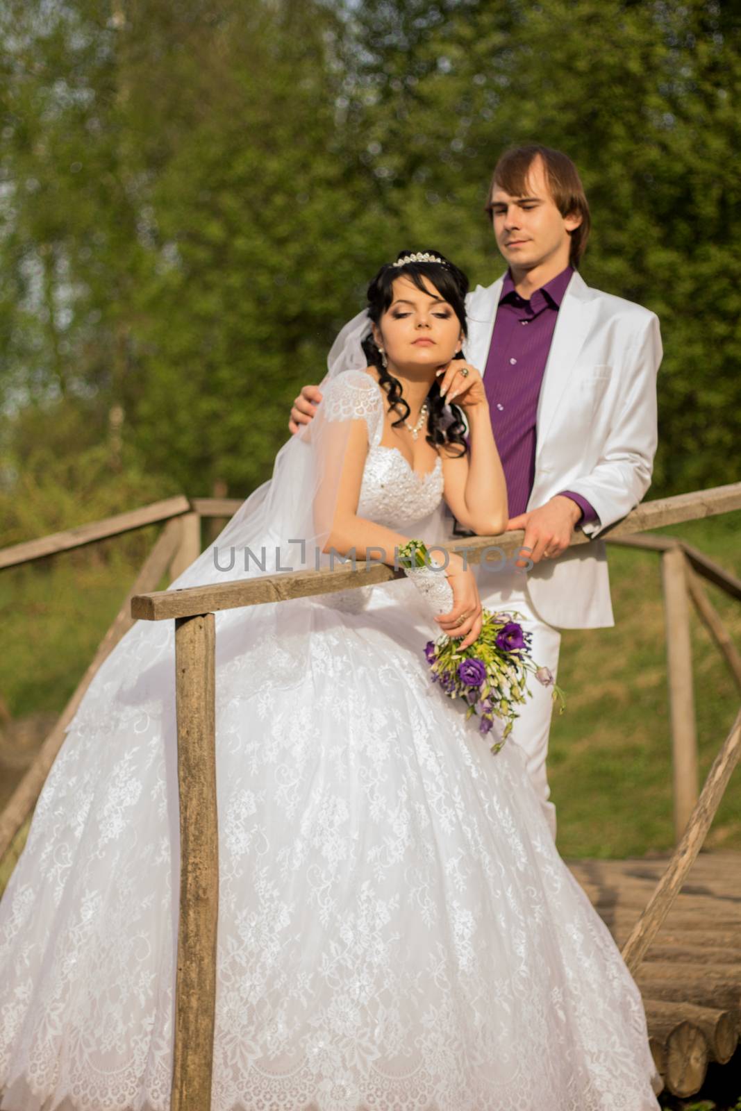 Happy just married couple standing on the small bridge.