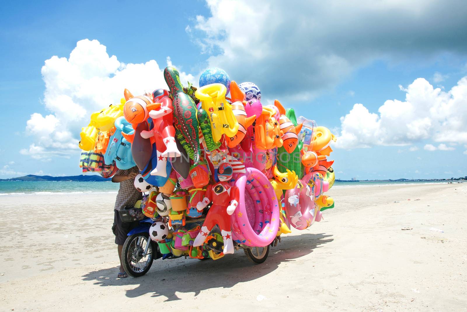 RAYONG,THAILAND-MAY 07,2015 :The man ride mobile shop selling toys to child  on the beach in Eastern Thailand.