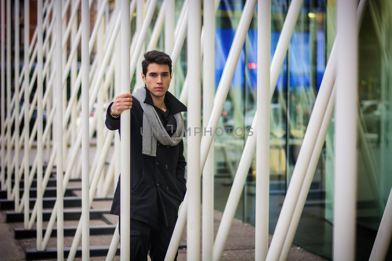 Young Handsome Man among White Metal Bars by artofphoto
