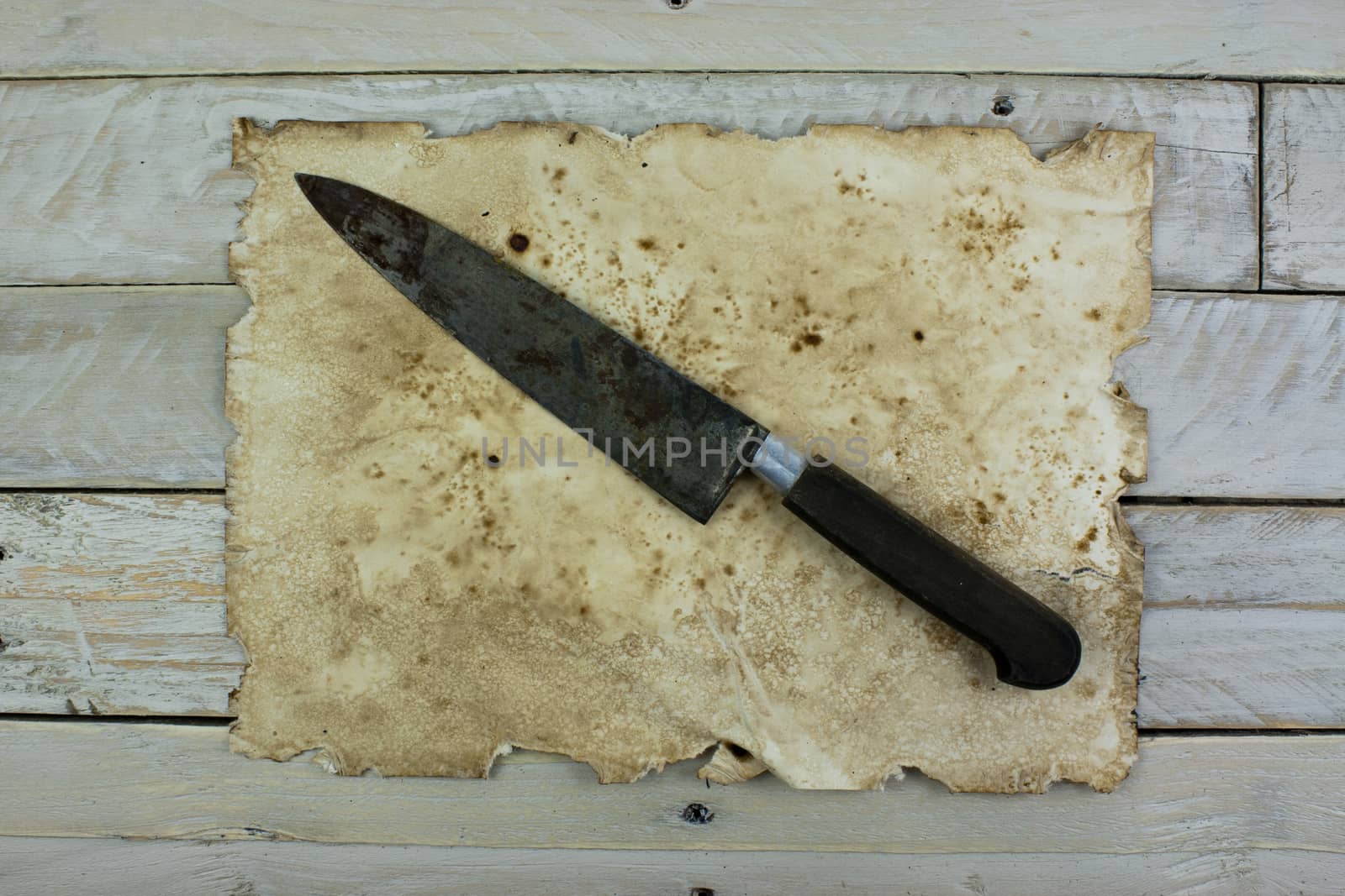 Piece of old paper and a knife on wooden planks