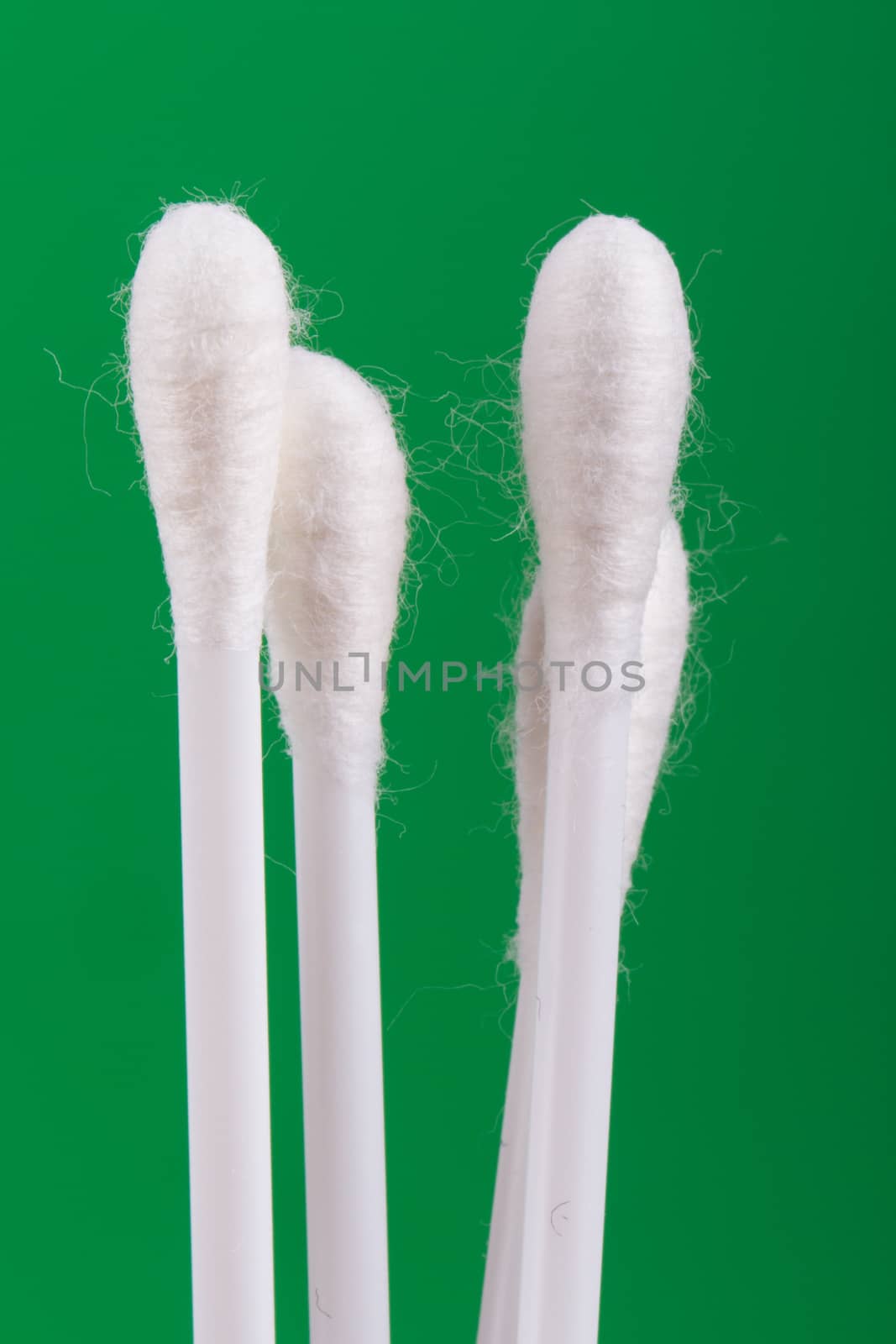 White cotton swabs on green background.