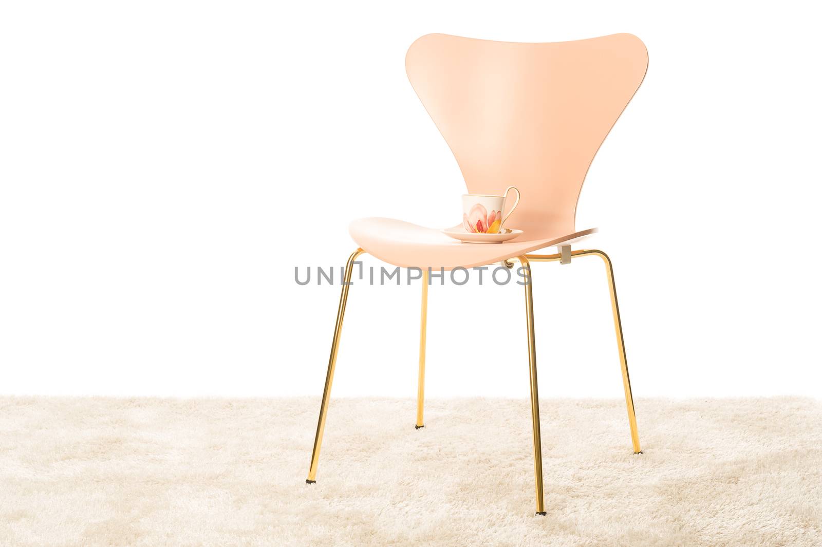 Stylish moulded modern chair with metal legs and a porcelain teacup standing on the vacant seat in a room interior with a white wall and copyspace