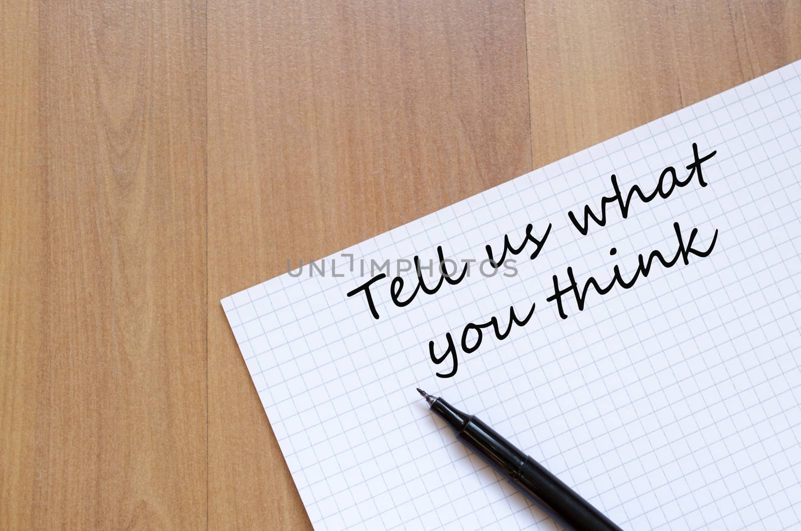 White blank notepad on office wooden table Tell us concept