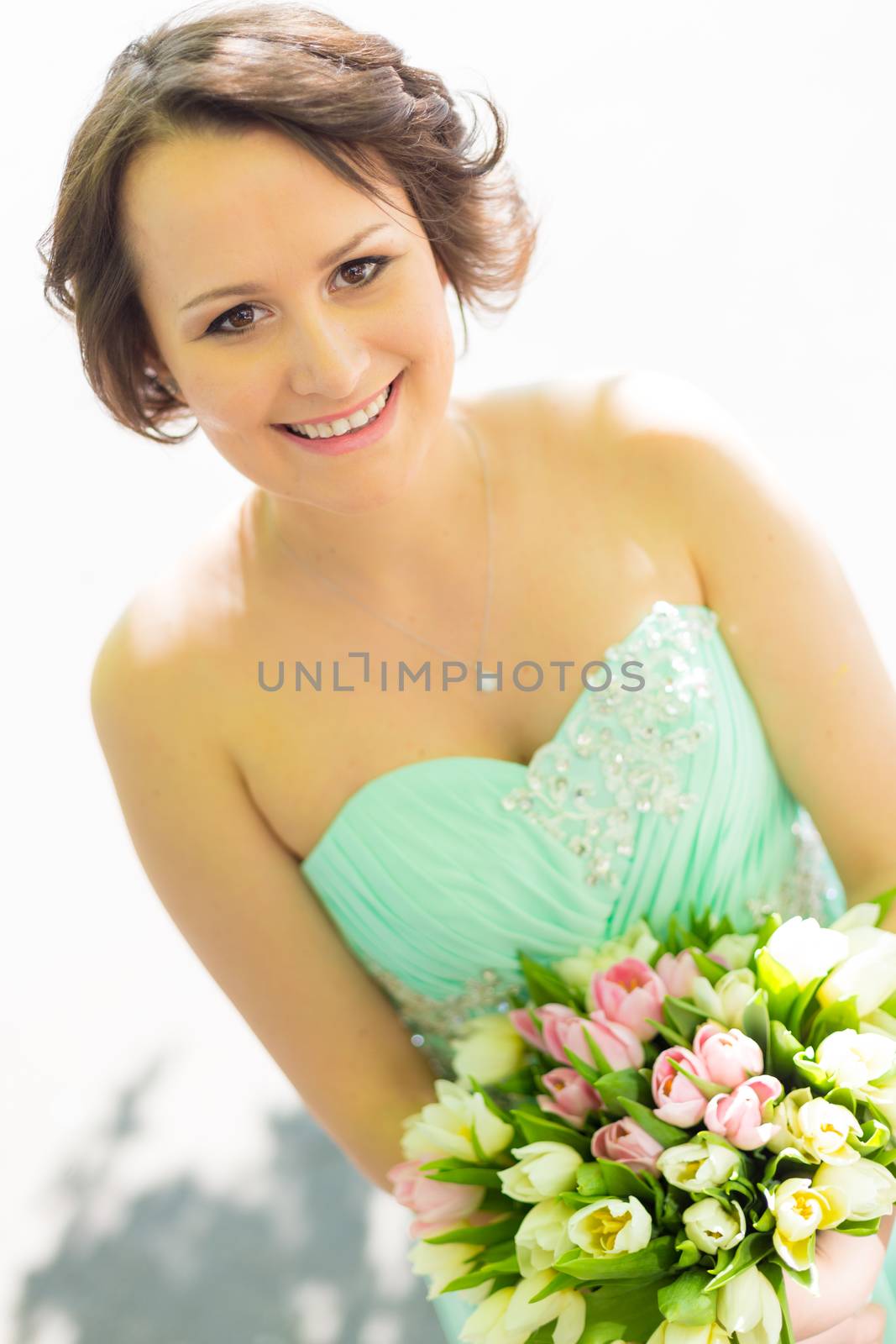 Portrait of a beautiful woman in green dress holding a colorful bouquet of tulips.