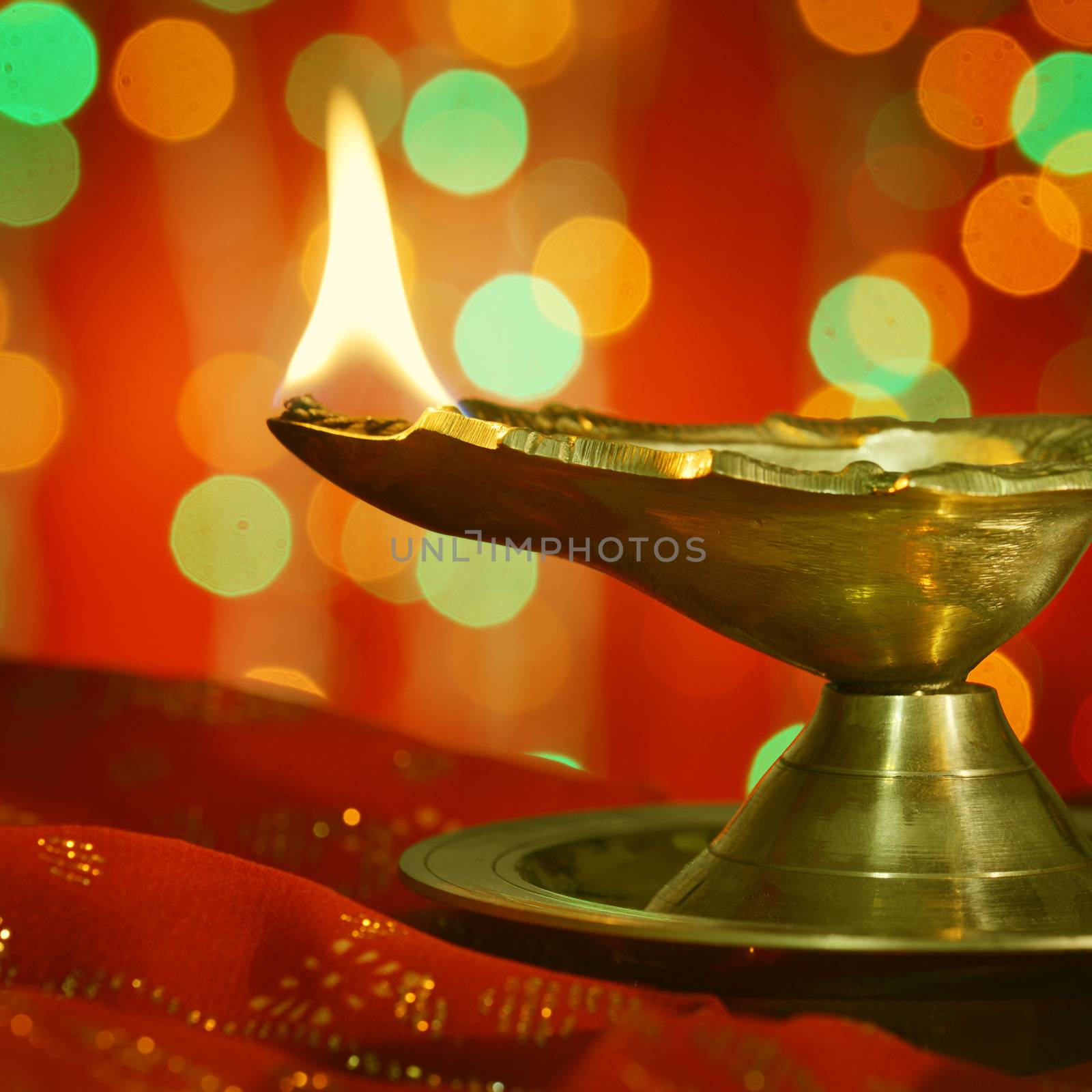 A metallic traditional Indian lamp illuminated in dark. Diwali Greetings.