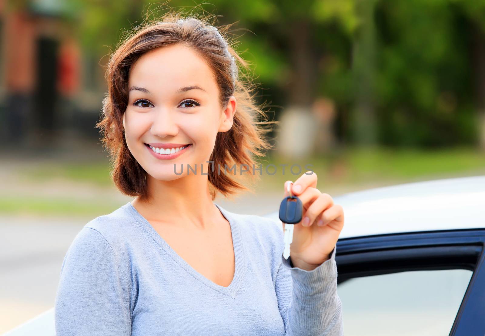 Happy girl with a car key smiling