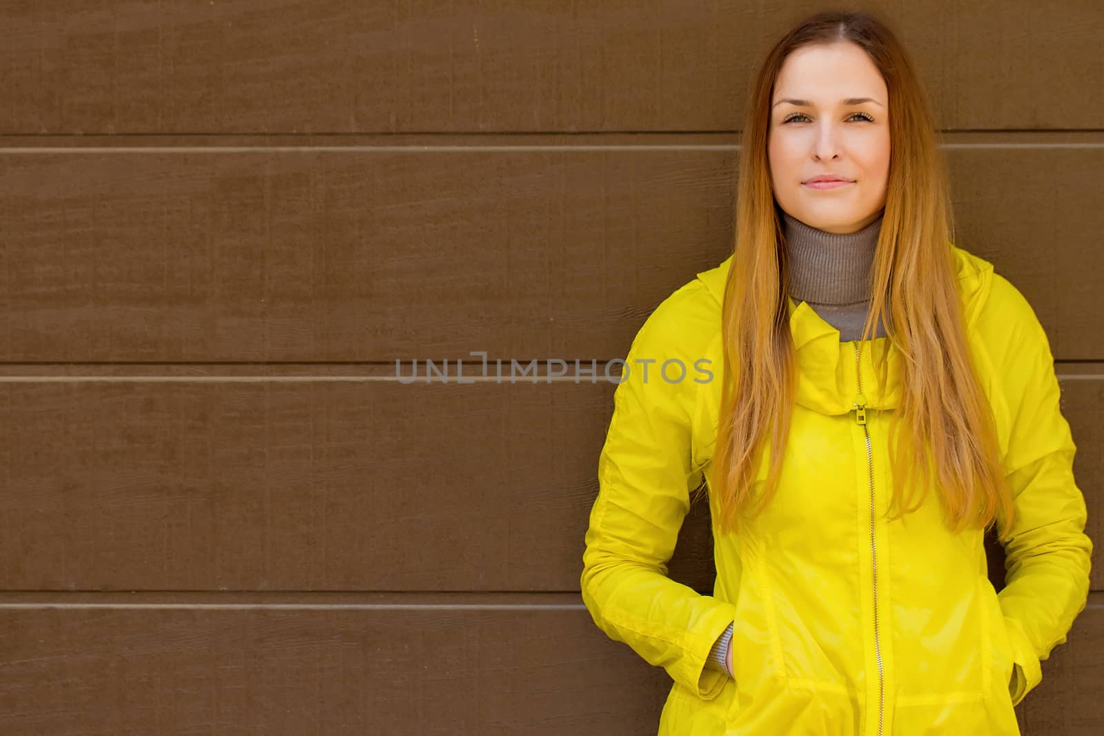 Beautiful fashionable girl in a jacket  in autumn on a background of a wall