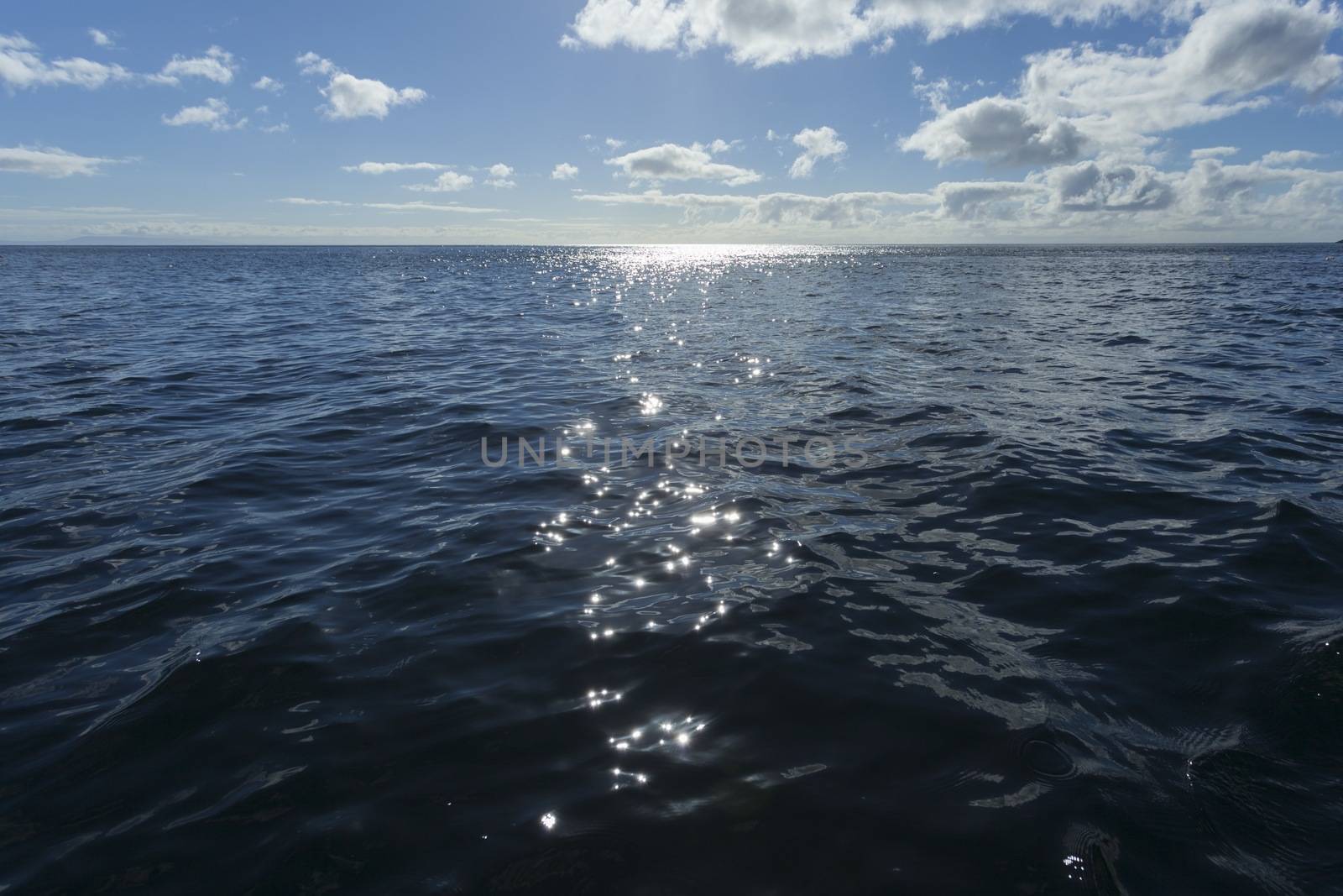 View of the open deep blue and a very calm altantic sea with the shimmering light of the sun on the surface