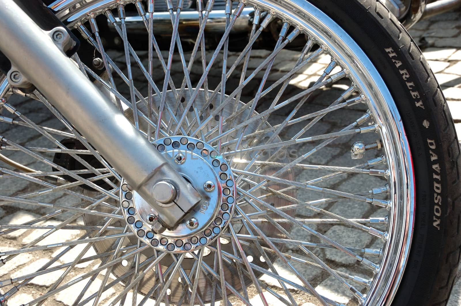 Closeup photo of motorcycle wheel with shiny spokes and metallic rim.