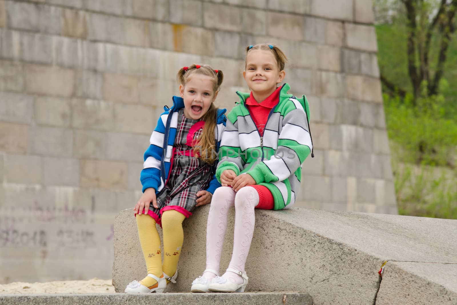 two girls of four and six years of walking on the embankment of the river