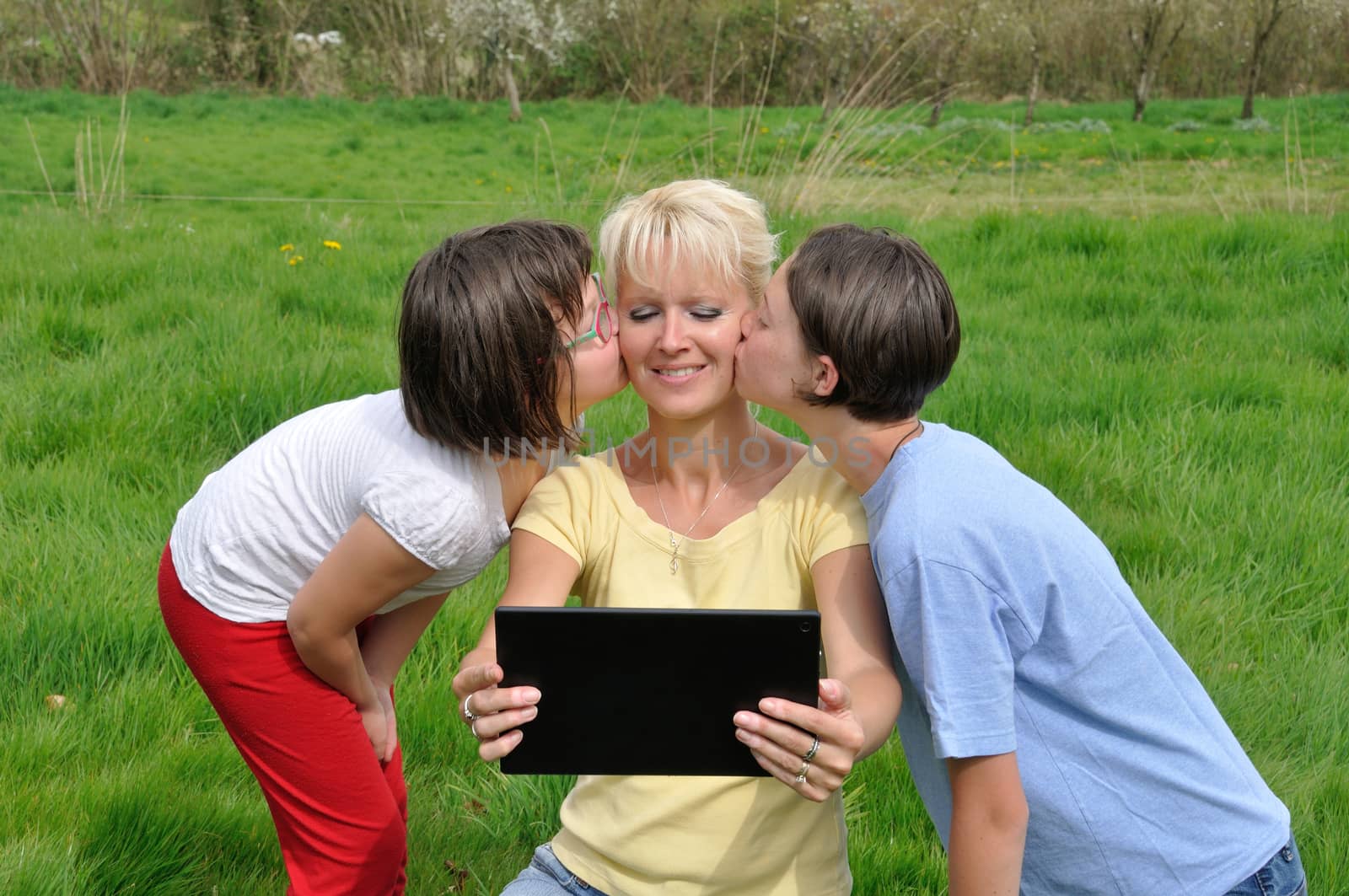 Family sitting on the lawn and using digital tablet