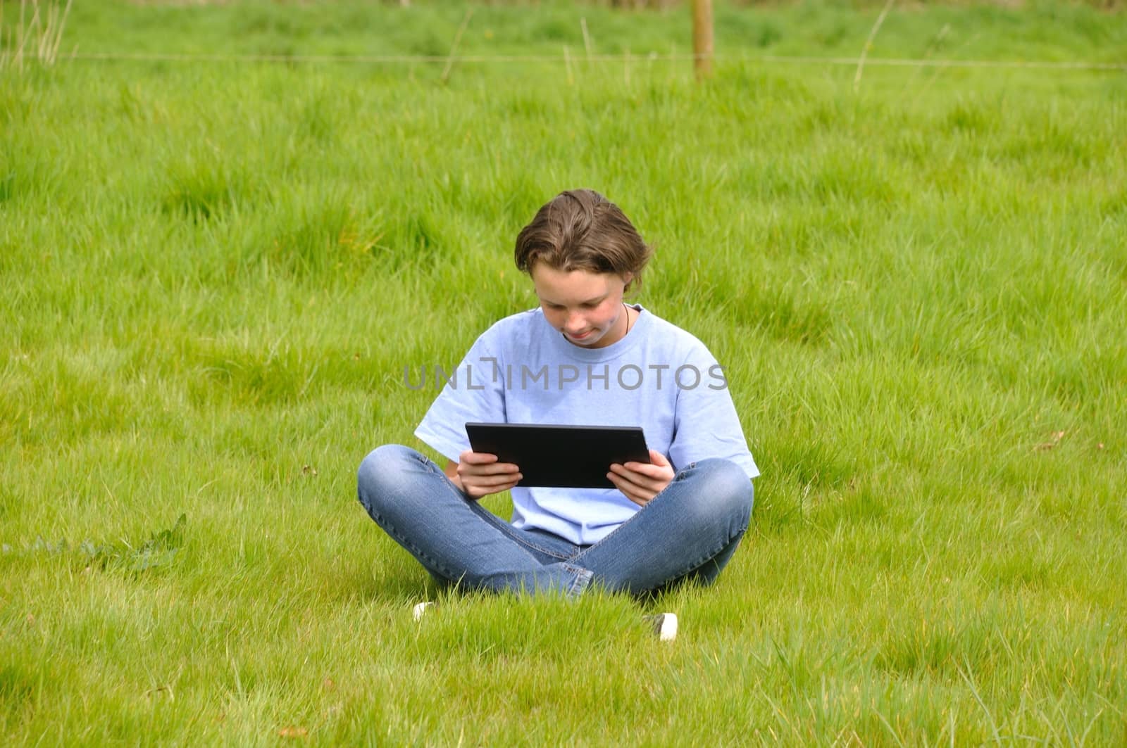 Girl sitting on the lawn and using digital tablet