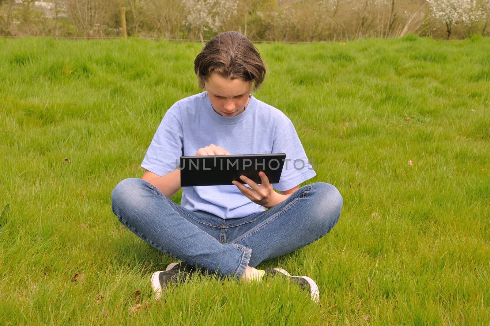 Girl sitting on the lawn and using digital tablet by BZH22