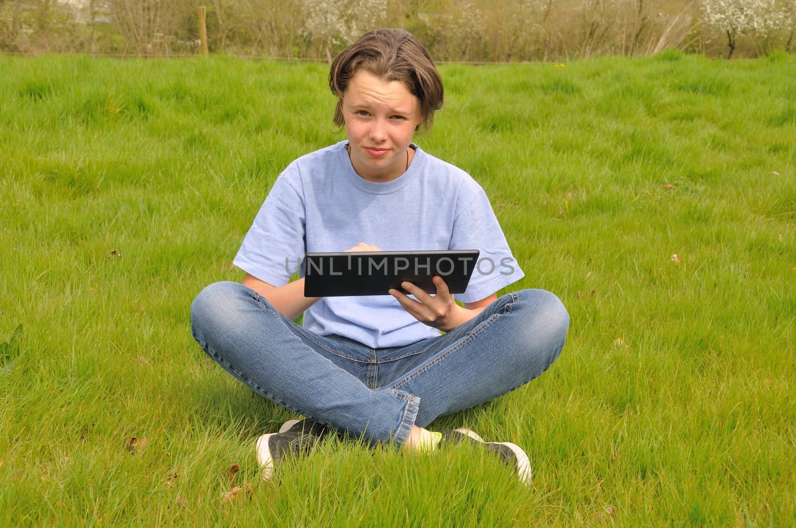 Girl sitting on the lawn and using digital tablet
