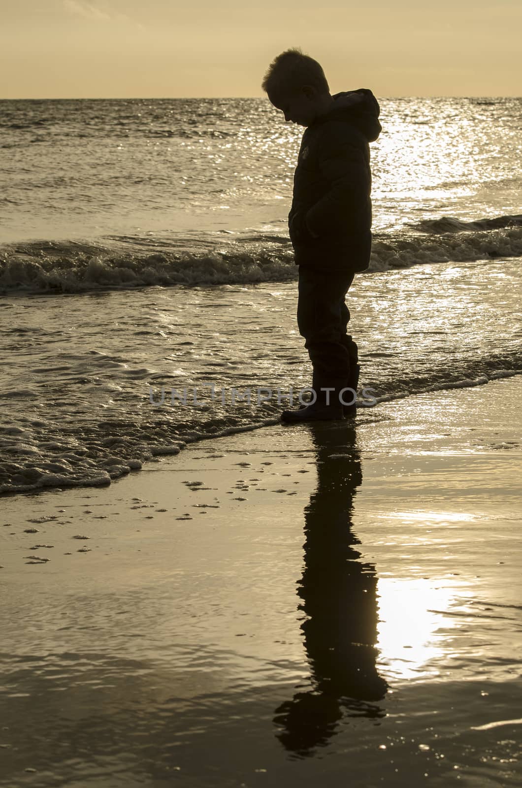 Silhouette and reflection of a little boy on the beach. by Tofotografie