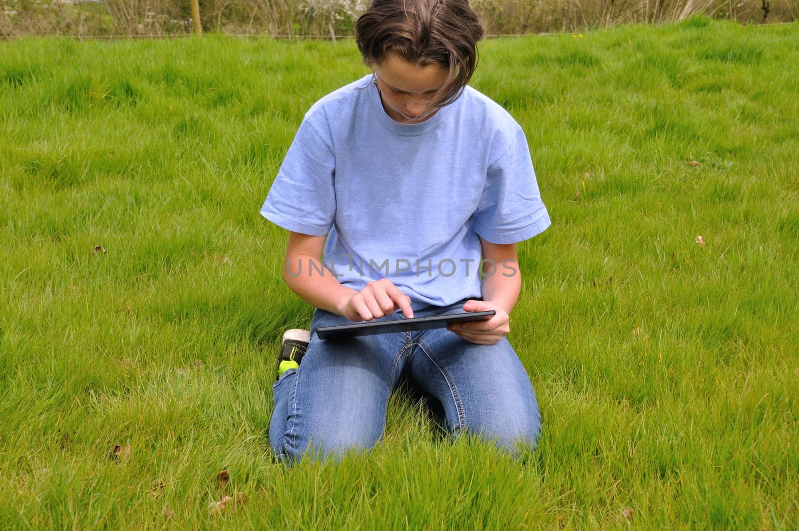 Girl sitting on the lawn and using digital tablet