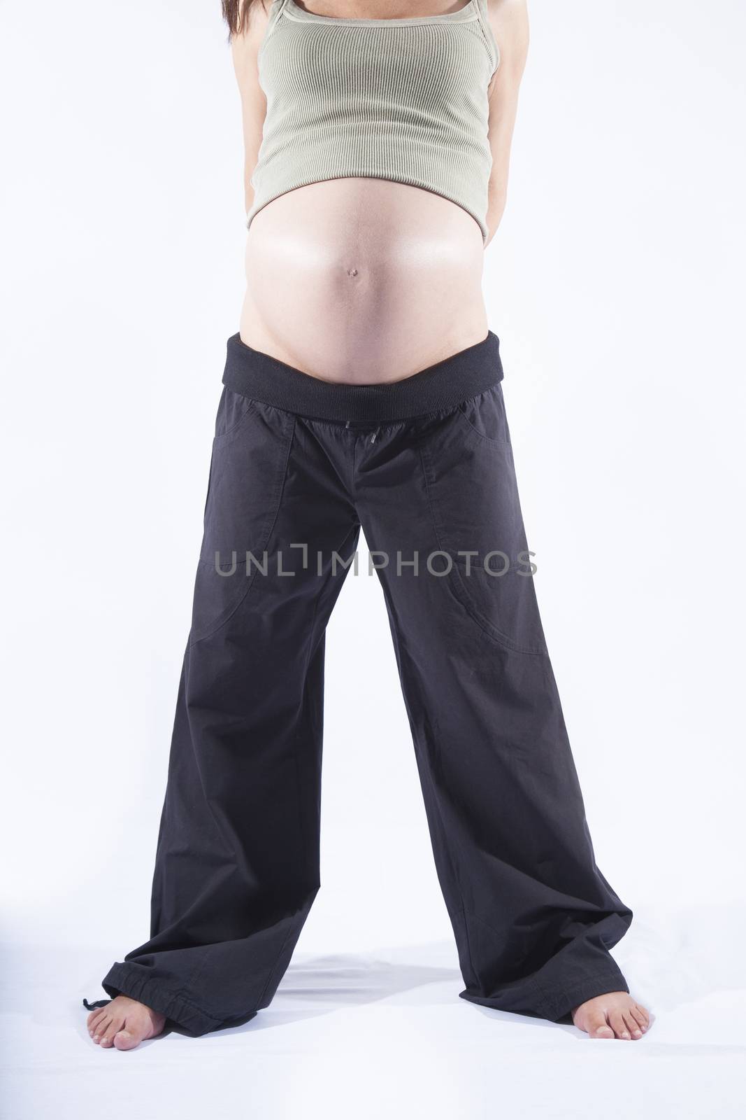front eight month brunette pregnant woman naked paunch standing black trousers isolated over white background