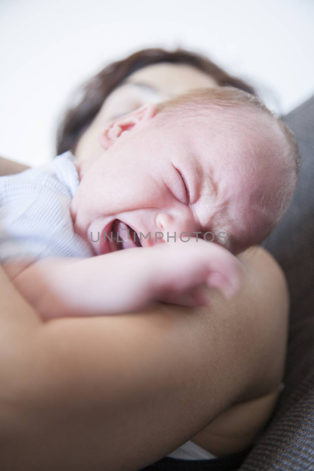 one month age baby crying and scream shout close eyes tongue on brunette woman mother shoulder