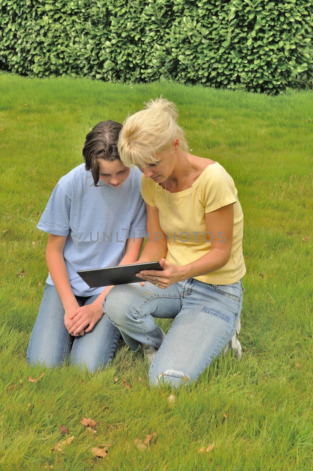 Family sitting on the lawn and using digital tablet by BZH22