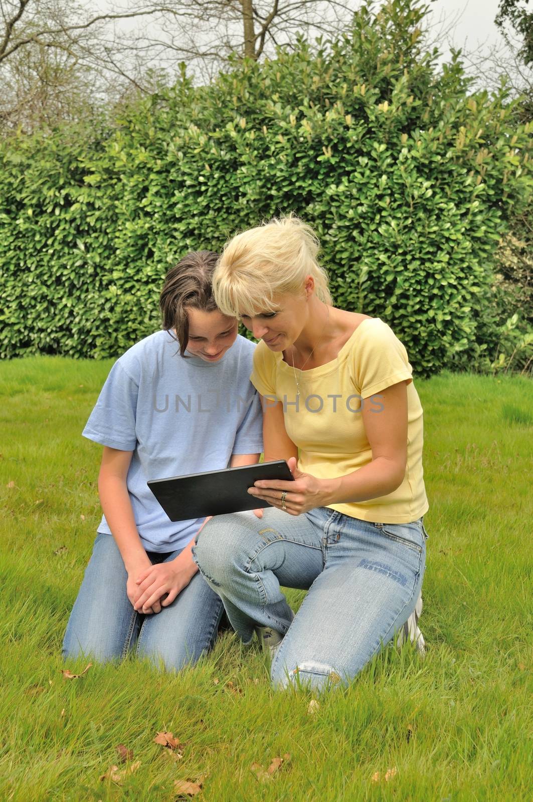 Family sitting on the lawn and using digital tablet