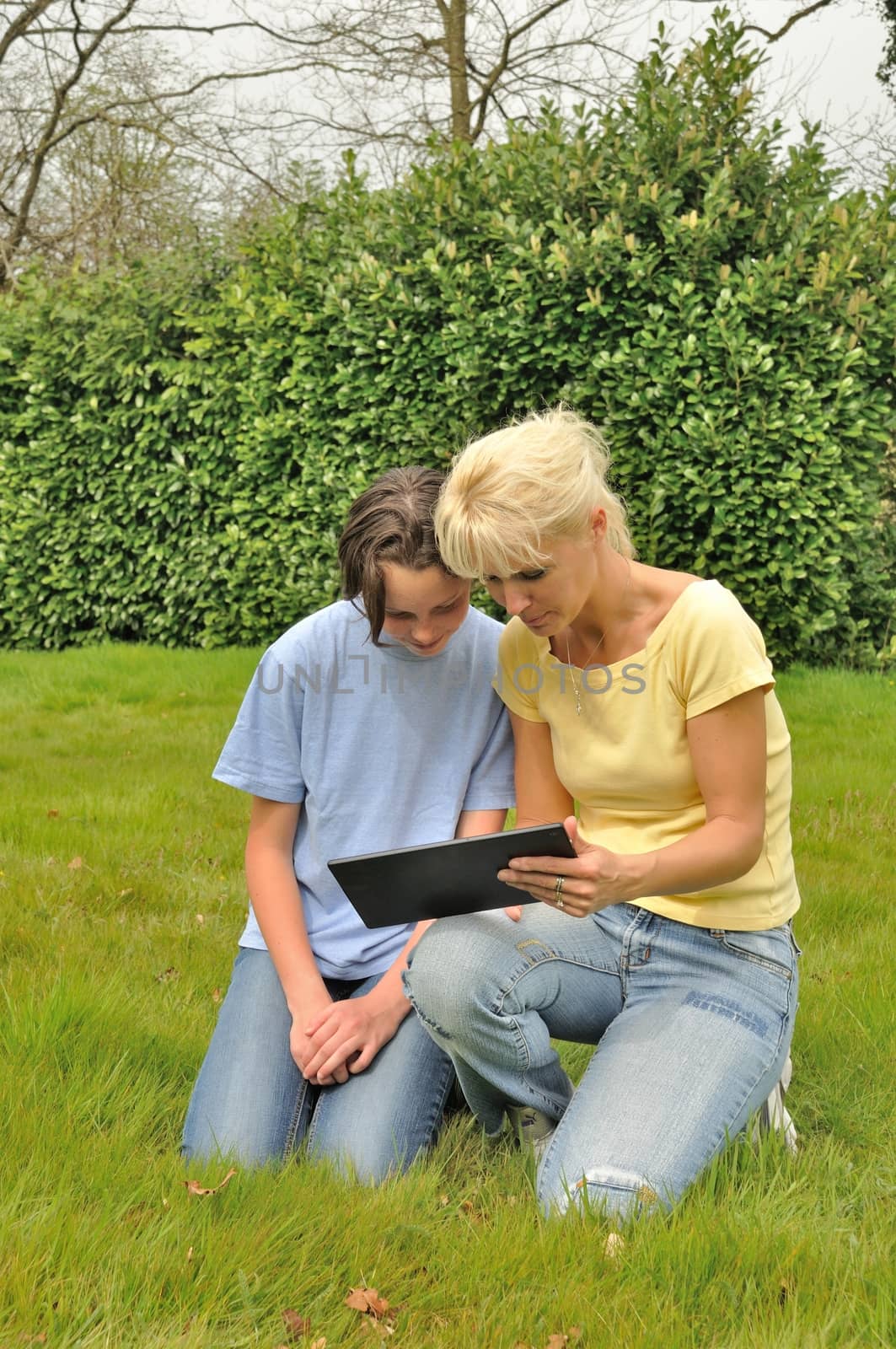 Family sitting on the lawn and using digital tablet