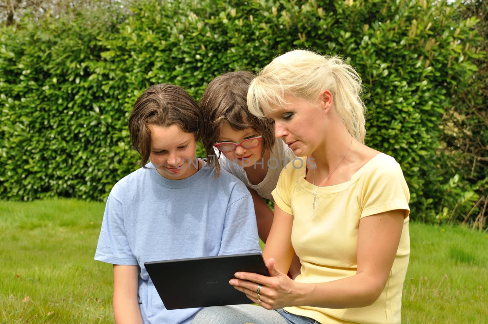 Family sitting on the lawn and using digital tablet